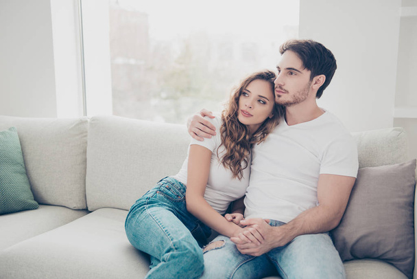 Weekend holiday daydream serenity concept. Portrait of attractive calm couple sitting on sofa in living room hugging looking away enjoying time together - Photo, Image