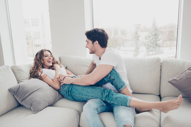 Portrait of funny comic spouses enjoying time together indoor laughing sitting on sofa in modern living room. Daydream mood inspiration concept - Foto, Imagem