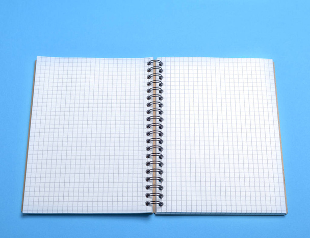 Άνοιγμα κενό σημειωματάριο σε ένα πλαίσιο σε μπλε φόντο, το top view - Φωτογραφία, εικόνα