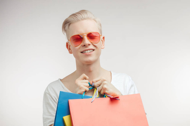 Portrait of fashion young man in pink glasses with shopping bags - Fotoğraf, Görsel
