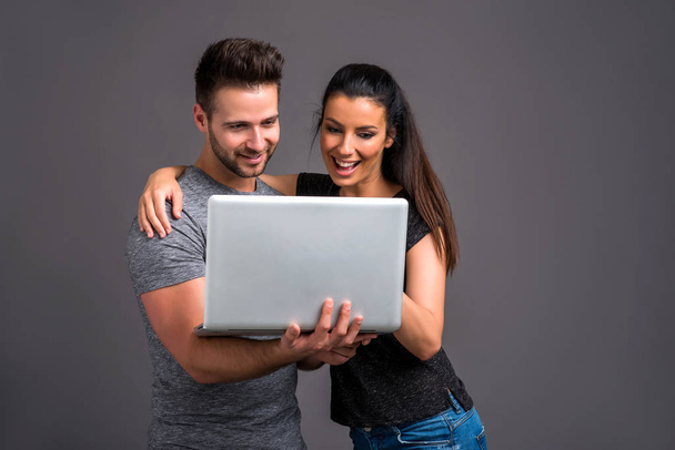 A beautiful young couple looking at a laptop and smiling - Foto, Imagen