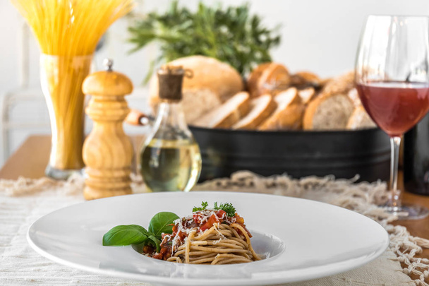 Food composition of spaghetti topped with delicious bolognaise sauce and basil served on table - Фото, изображение