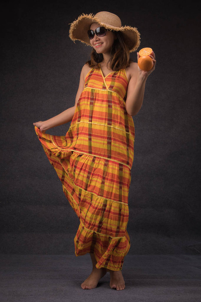 Aasialainen nainen pitkä kirkas mekko tilalla appelsiinit seisoo studiossa
 - Valokuva, kuva