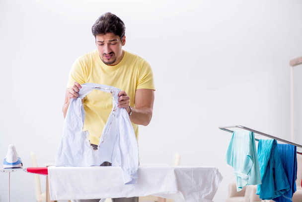 Όμορφος άντρας που σιδερώνει ρούχα στο σπίτι. - Φωτογραφία, εικόνα