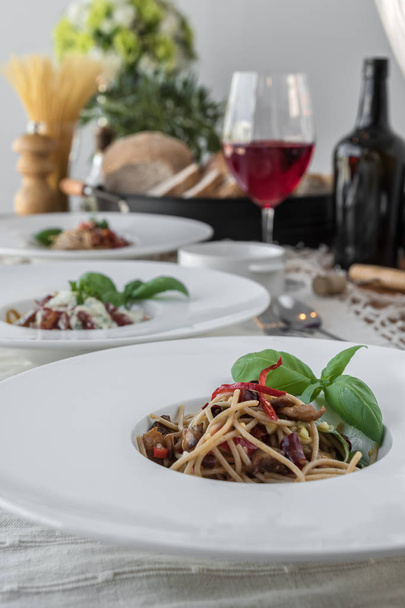 Food composition of plates of spaghetti topped with delicious bolognaise sauce and basil - Fotó, kép