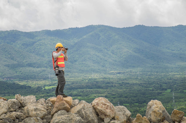 Engineer using binoculars with mountains on background. - Photo, Image
