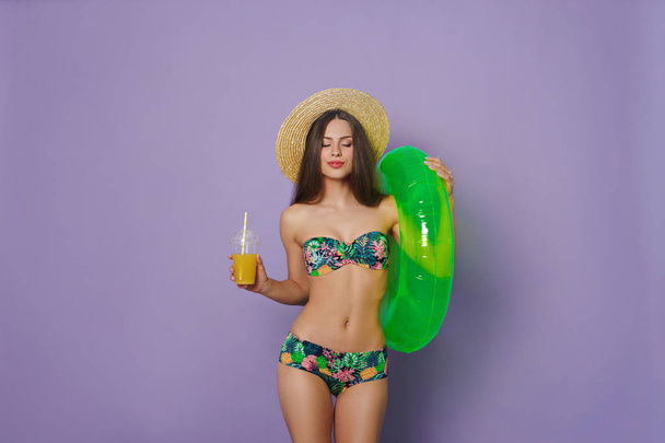 beautiful young woman with inflatable ring and juice - Photo, Image