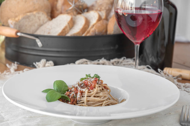 Food composition of spaghetti topped with delicious bolognaise sauce and basil on table - Fotó, kép