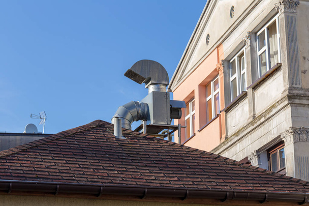 Ventilation chimney on the roof with gutter near old apartment house - Фото, изображение