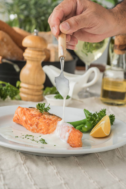 Chef serving and adding white sauce to salmon steak - Φωτογραφία, εικόνα