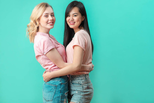 Multiethnic young women hugging at blue studio background with copy space - Photo, image