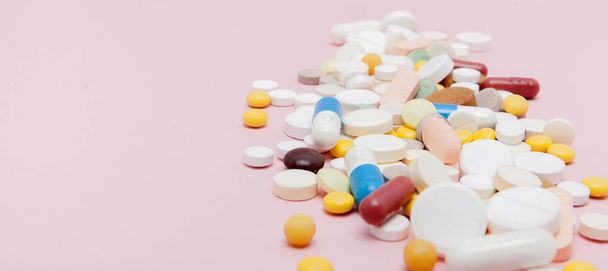 Colorful tablets with capsules on a pink background. - Fotó, kép