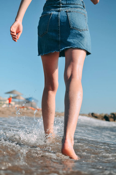 Mladá dívka vede podél moře, písčité pláže naboso, koncept, nohy. Spodní pohled zezadu - Fotografie, Obrázek