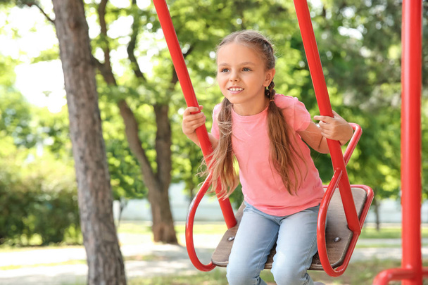Cute little girl playing on swings in park - Foto, afbeelding
