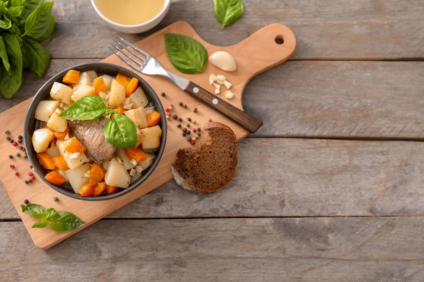 Bowl with tasty meat and potatoes on wooden board - Foto, immagini