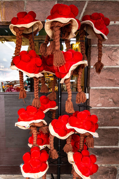 Kolorowy czerwony tradycyjne wełniane bollenhut, część regionalnych strojów ludowych, wiszące na statywie poza sklep w regionie Schwarzwald - Zdjęcie, obraz