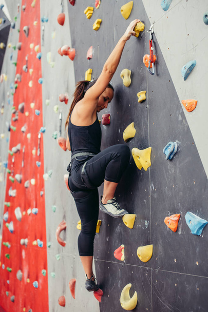 Sporty young woman training in a colorful climbing gym. - Photo, image