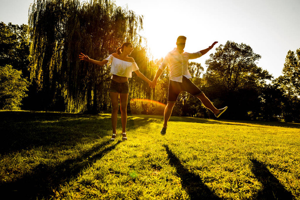 Un beau jeune couple sautant sur un terrain au coucher du soleil
 - Photo, image