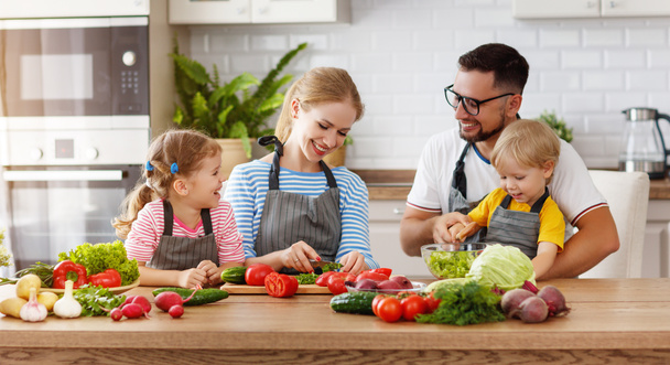 щаслива сім'я з дитиною готує овочевий салат вдома
 - Фото, зображення
