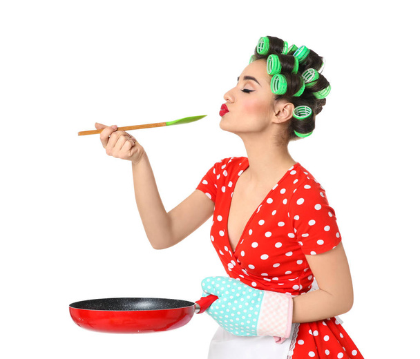 Funny young housewife with spoon and frying pan on white background - Foto, imagen