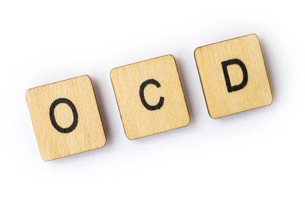 The abbreviation OCD - Obsessive Compulsive Disorder - spelt out with wooden letter tiles. - Фото, изображение
