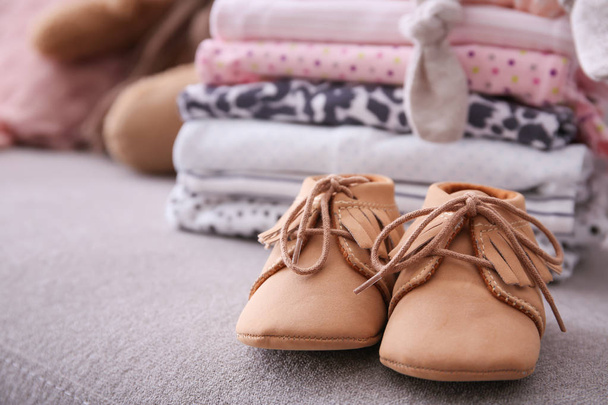 Child shoes and stack of clothes on background - Foto, Bild