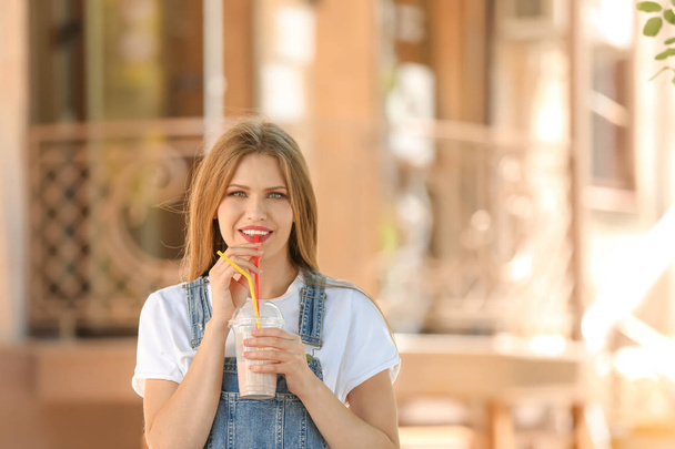 Young woman with cup of delicious milk shake outdoors - 写真・画像