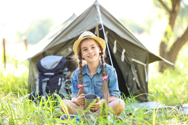 Little girl with mug near tent outdoors. Summer camp - Foto, afbeelding
