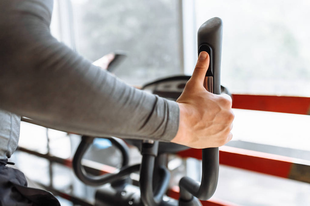Training on a sports bike in the gym, hand close-up holding the handle of the bike, man - Fotoğraf, Görsel