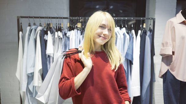 Молода блондинка щаслива усміхнена жінка щойно купила одяг у магазині
 - Фото, зображення