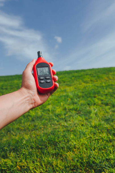 portable thermometer in hand measuring outdoor air temperature and humidity - Foto, Imagem