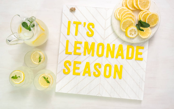 Es letrero de madera de temporada de limonada con limones recién cortados en rodajas en una tabla de cortar madera
. - Foto, Imagen