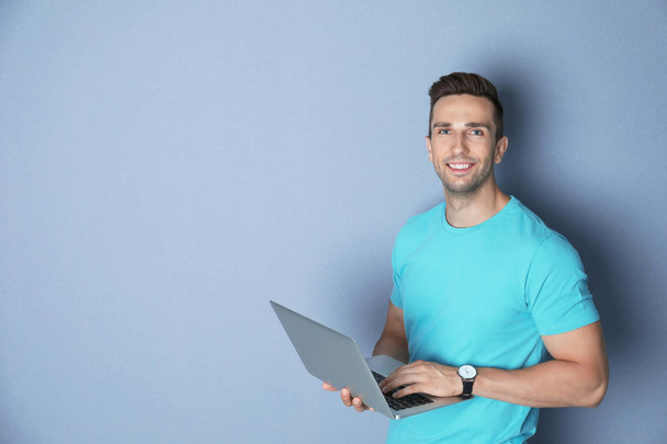 Man in casual clothes with laptop on color background - Фото, зображення