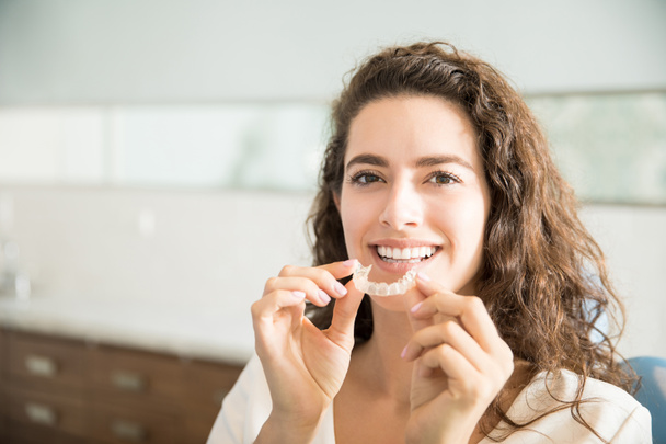 Portrét krásné pacienta hospodářství ortodontické přívrženci v zubní klinice - Fotografie, Obrázek