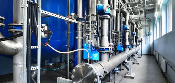 Große industrielle Wasseraufbereitung und Heizraum. Glänzende Stahlrohre und blaue Pumpen und Ventile. - Foto, Bild