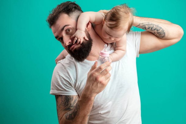 Playful father carrying his smiling infant child on neck over blue background - Foto, Imagen
