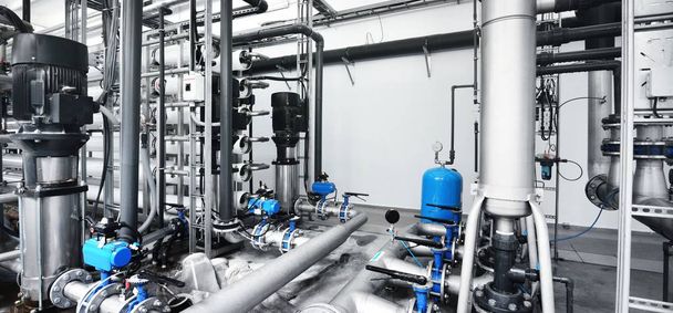 Ampio locale trattamento acque industriali e caldaia. Tubi metallici in acciaio lucido e pompe e valvole blu. - Foto, immagini