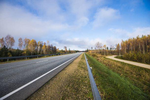 A view of the asphalt country road in Latvia on a clear autumn day - Photo, Image
