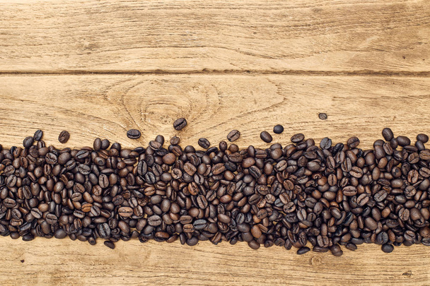 Grãos de café preto jazem em uma mesa de madeira marrom, fundo
  - Foto, Imagem