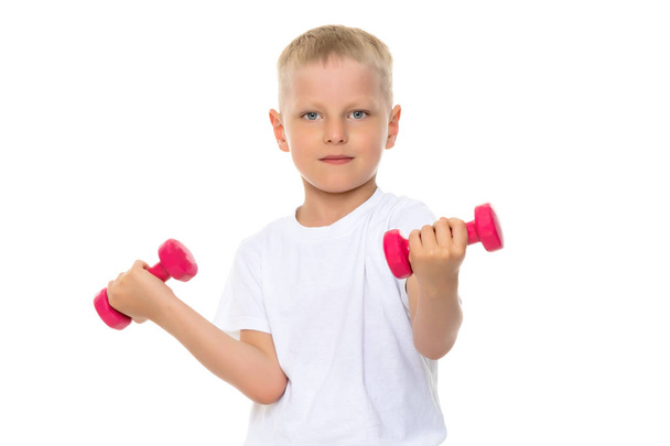 A little boy is lifting dumbbells. - Zdjęcie, obraz