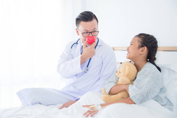 Lekarz pediatra trzymając piłkę czerwone serce na nos, grając z chorego dziecka - Zdjęcie, obraz