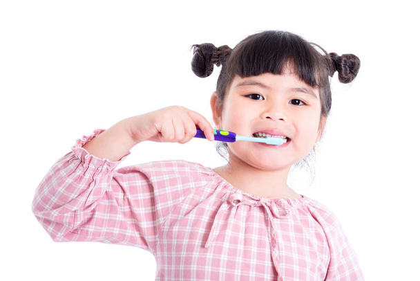Petite fille asiatique tenant brosse à dents et sourires sur fond blanc
 - Photo, image