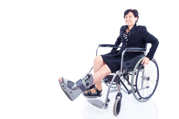 Asian businesswoman with leg brace sitting on wheelchair and smiles - Valokuva, kuva