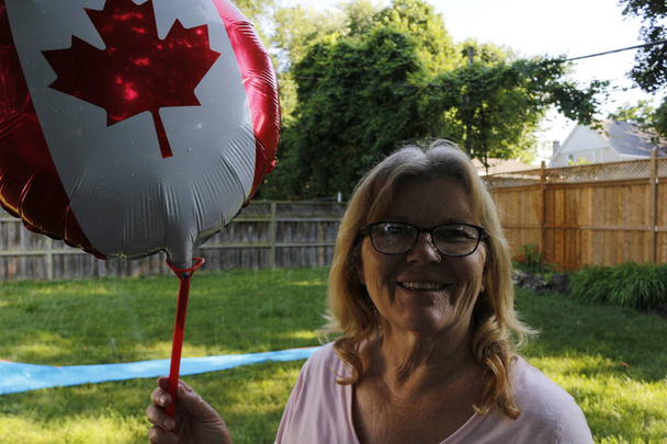 Ανώτερες γυναίκες ηλικίας 60 έως 65 που κρατούν ένα καναδικό μπαλόνι ημέρας για να είναι πατριωτικά - Φωτογραφία, εικόνα