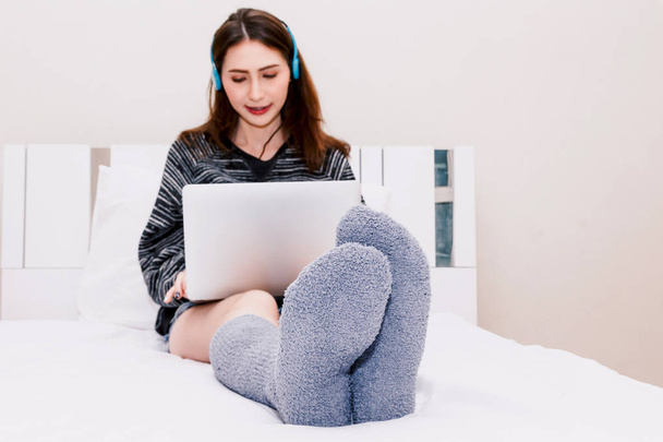 Frau benutzt Laptop auf weißem Bett zu Hause - Foto, Bild