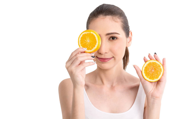 Όμορφη γυναίκα κρατώντας φέτα πορτοκάλι, κρύβοντας τα μάτια του πίσω από απομονωμένα σε λευκό φόντο - Φωτογραφία, εικόνα