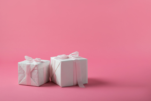 Two gift boxes with bows on pink background - Valokuva, kuva