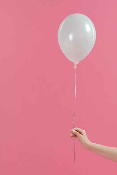 Vista recortada de una mujer sosteniendo un solo globo blanco aislado en rosa
 - Foto, Imagen