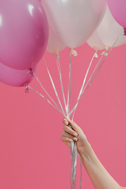 Female hand holding air balloons isolated on pink - Foto, Imagem