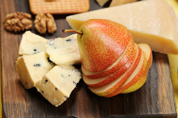pear cut into slices, cheese and walnuts on a wooden board - healthy food - Foto, Imagem